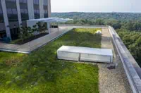 Aerial view: Atlanta commercial roof with grassy area, structures, and pebbled edge nearby.