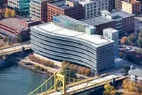 Aerial view of curved commercial building with flat roof by Pittsburgh, PA river