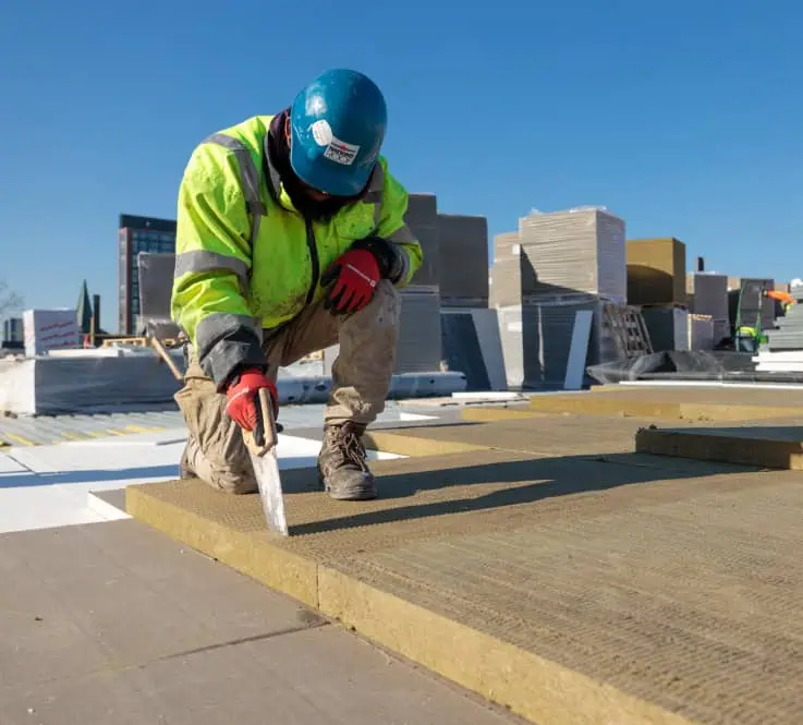 Worker Cutting Insulation Boards on Commercial Roof Site