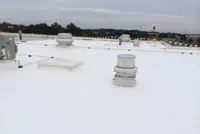 Commercial flat white TPO rooftop in Grand Rapids with vents under overcast sky