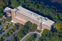 Aerial view: Quakertown multi-story brick building, lush trees, parking lots.