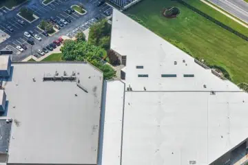 Aerial view of commercial flat roofs, parking lot, and landscaping, showcasing structured layout.