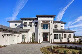 Contemporary two-story home with white exterior and double garage under blue sky - Florida roofing.