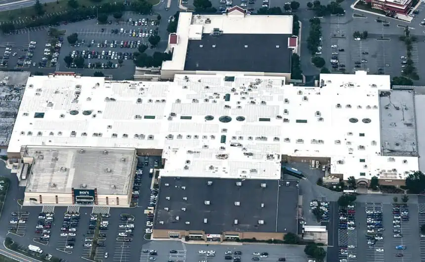 Aerial view of commercial building with skylights, vents, and full parking lots