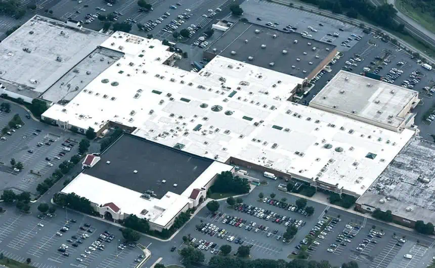 Aerial view of large mall with white TPO roof and busy parking lot.