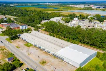 Aerial view: Industrial area with a large warehouse, TPO roofing, meandering roads.