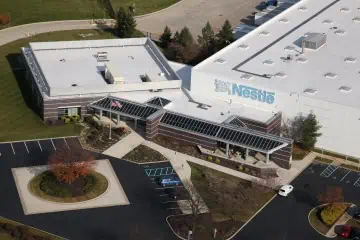 Aerial view of Nestlé facility with white commercial roof, parking lot, and logo.