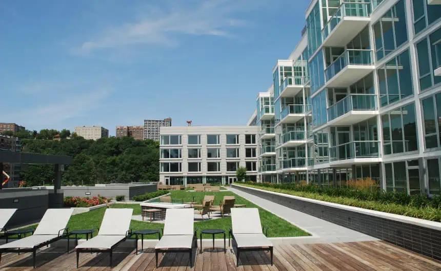 Modern apartment with large glass windows, rooftop lounge, and spacious lawn in Port Imperial.