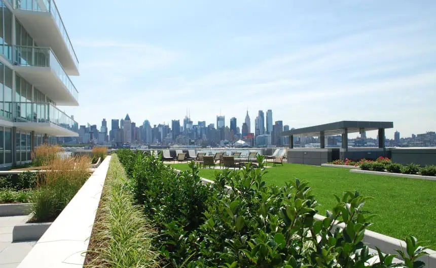 Rooftop garden with lawn, shrubs, seating, Port Imperial skyline view.

