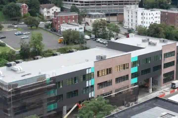 Aerial view: Commercial flat roof installation on multi-story building with construction equipment.