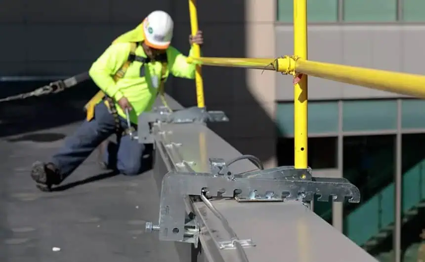 Worker secures rooftop safety railing at manufacturing plant