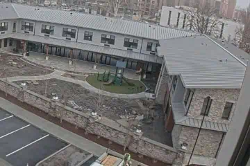 Two-story brick building with gray metal roof and courtyard playground