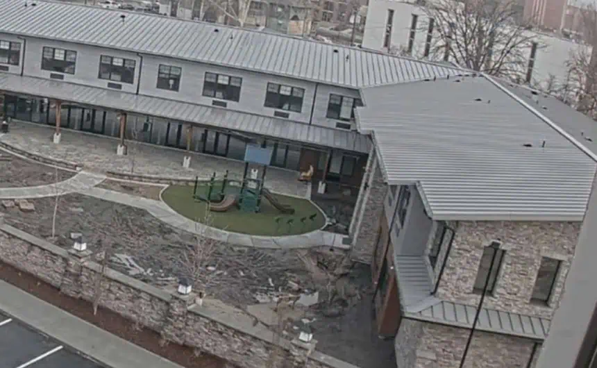 Urban courtyard with metal roofs on stone buildings and playground.