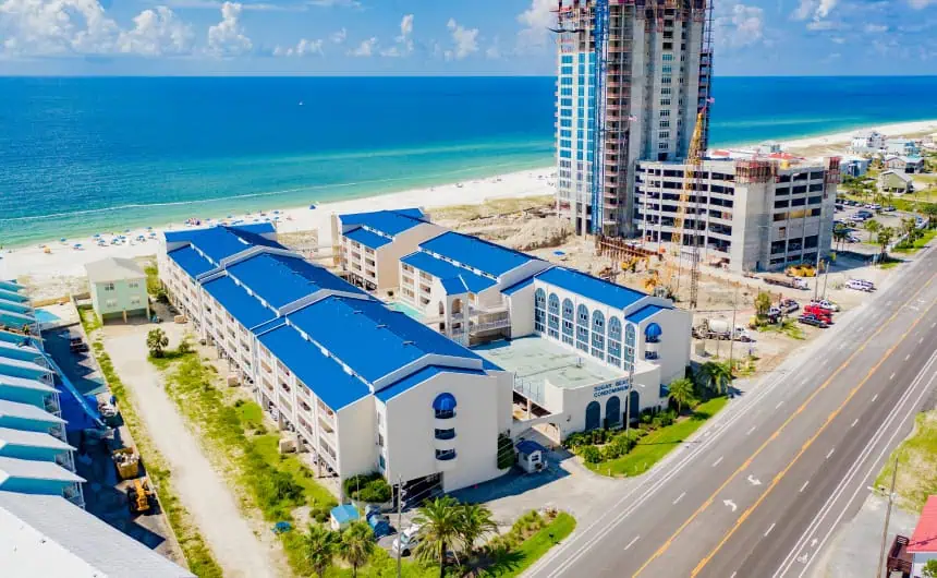 Aerial view: Roofing installation at beachfront condos with blue roofs near construction.