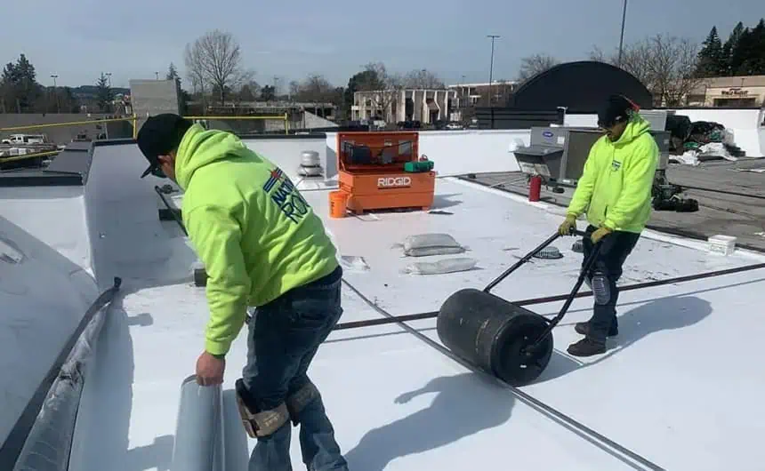 Neon-clad workers installing commercial roofing on flat roof in Portland