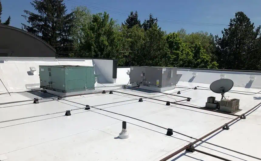 Oregon commercial flat roof with HVAC units, satellite dish, and piping.