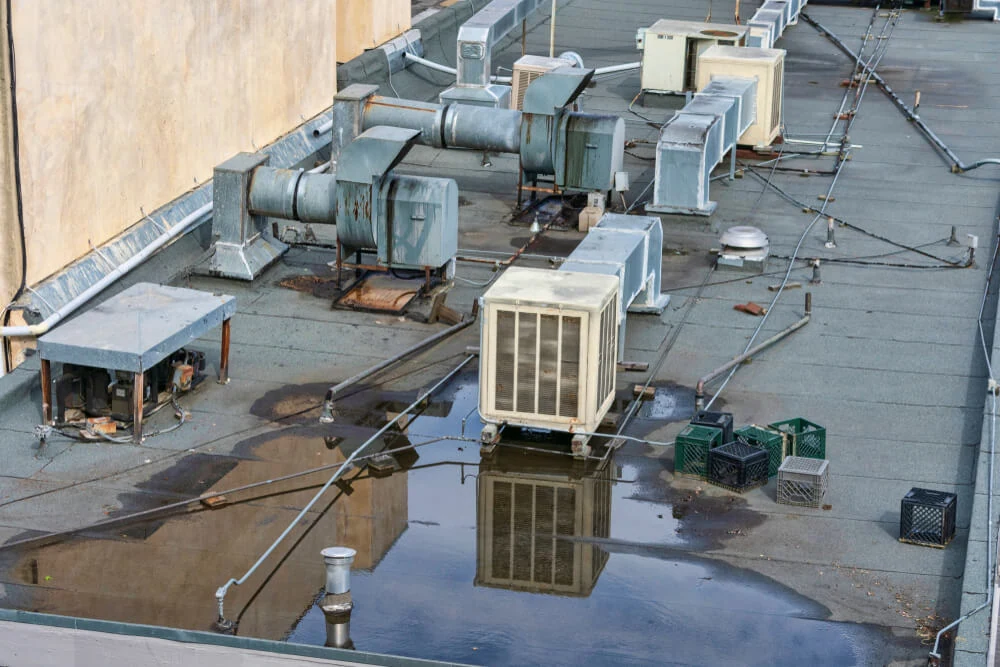 A black commercial roof with HVAC equipment with water ponding occurring