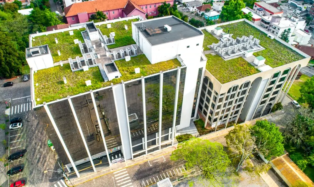 Aerial view of two green-roofed modern offices featuring flat and metal roofs, TPO roofing, and surrounded by trees and roads.