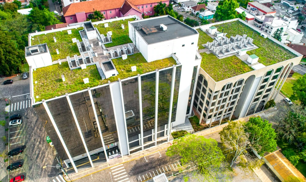 Aerial view of two commercial buildings with green flat roofs featuring EPDM roofing, roof maintenance elements, and surrounded by nature.