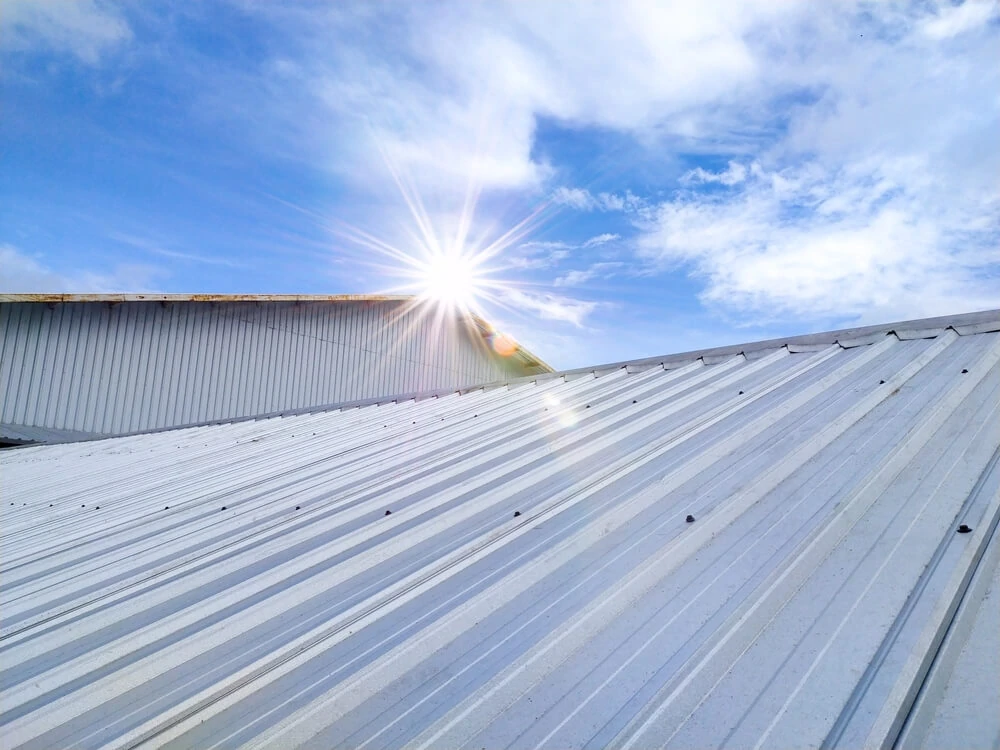 Sunlight highlights the potential of metal roofing for commercial buildings under a partly cloudy sky, ideal for roof maintenance.