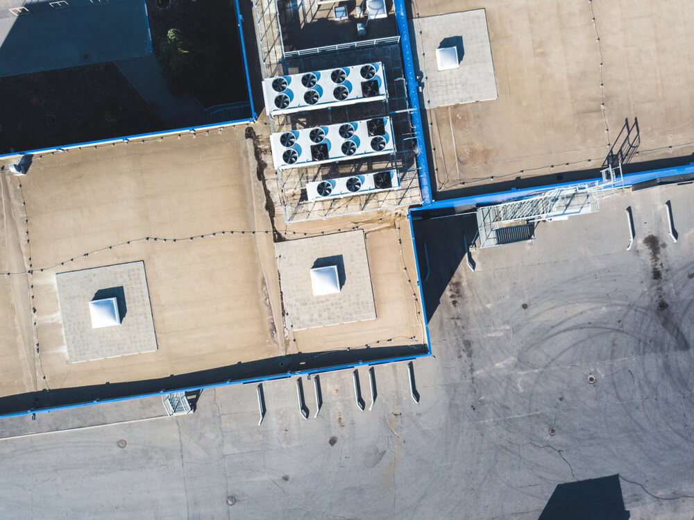 The edge of a commercial roof with multiple HVAC units.